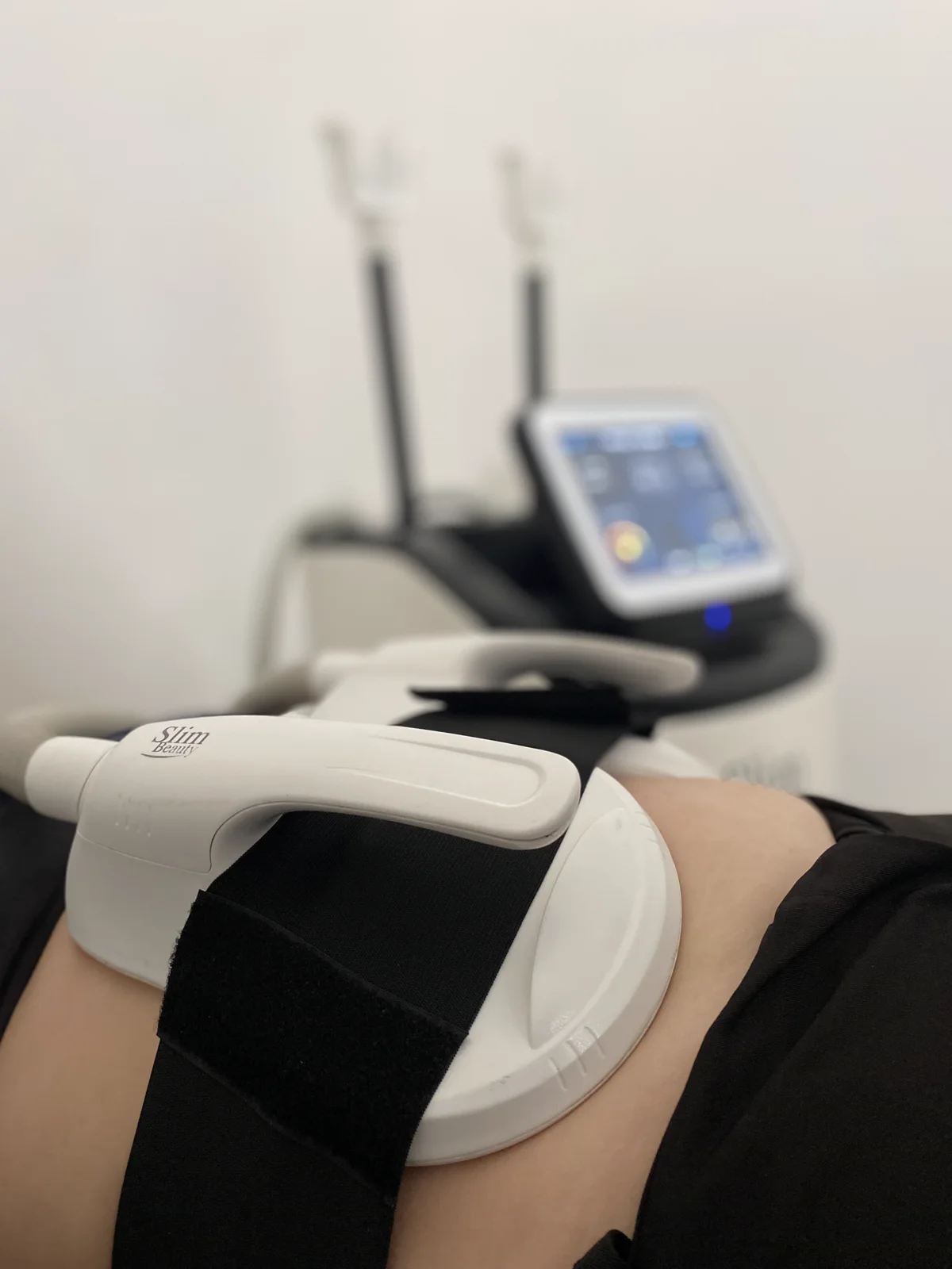 Sesión de SculptFit en Antoá: el aplicador electromagnético sobre el abdomen de la clienta, fijado con banda, junto a la consola del equipo